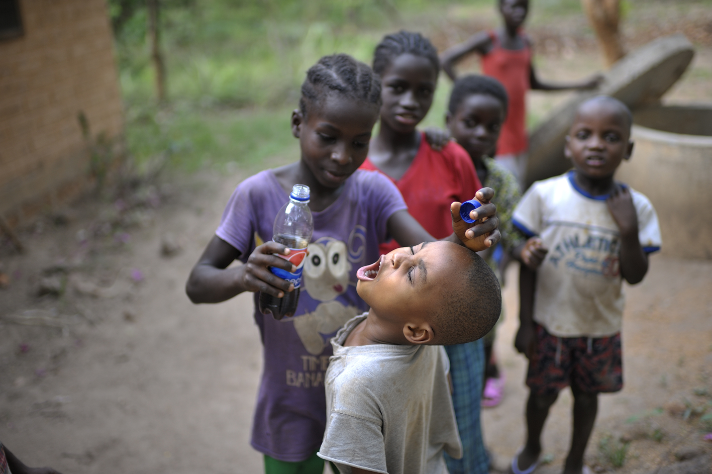 Ein Mädchen verteilt Cola an Spielkameraden in Nigeria. © Tobias Strahl